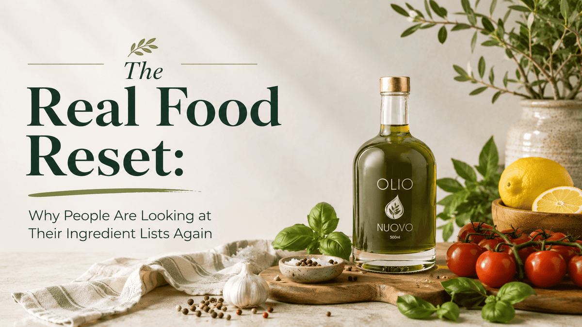 Olio Nuovo olive oil bottle with fresh tomatoes, basil, garlic and lemons beside “The Real Food Reset” blog title.